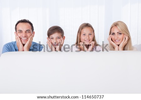 Portrait Of  Happy Family Behind White Sofa, Indoors