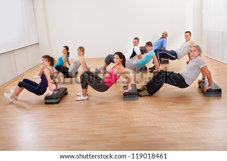 Large group of diverse people working out together in a gym doing balance and muscle control exercises with copyspace