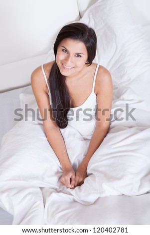 Pretty Young Woman Snuggling Down In Bed As She Smiles Up At The Camera ...