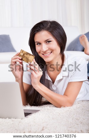 Woman shopping online holding her credit card in her hand as she enters the details in payment for her purchase
