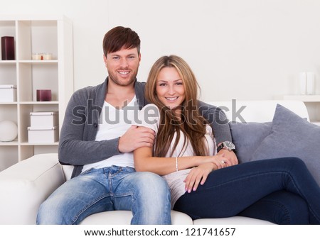 Couple sit on new couch bought at furniture shop.