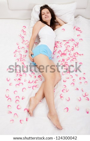 Young brunette woman relaxing on a bed with white bed covers