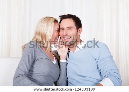 Laughing man and woman sharing a secret - or perhaps the man is licking her ear or kissing her