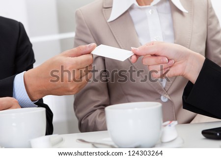 Businesspeople exchanging cards over coffee while having an informal meeting in a cafe