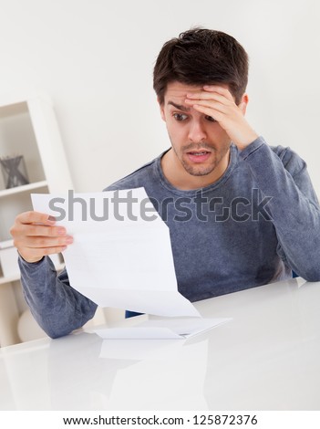 Horrified Young Man Reading A Document With An Aghast Expression And ...