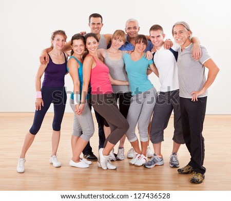 Large group of diverse male and female friends posing together at the gym in their sportswear