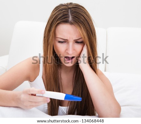 Worried Young Woman Checking Pregnancy Test At Home