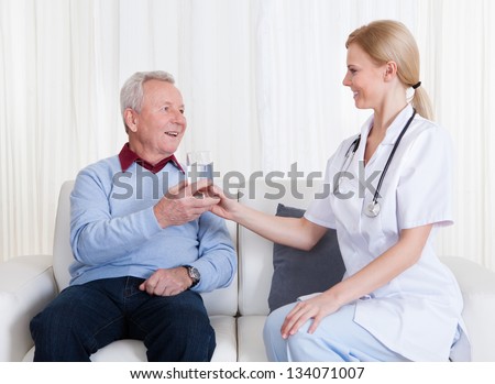 Caring Doctor Giving Water To Senior Patient; Indoor