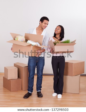 Portrait Of Young Couple Carrying Boxes In House