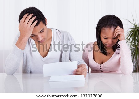 Portrait Of Worried Young Couple Looking At Paper