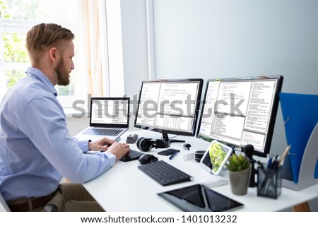 Photo of Computer programmer writing program code on computer in office 