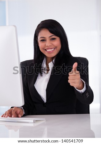 Young Businesswoman Working In Office And Showing Thumb Up Sign