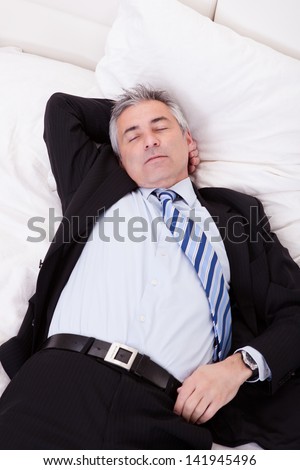 Portrait Of Thoughtful Mature Businessman Relaxing On Bed