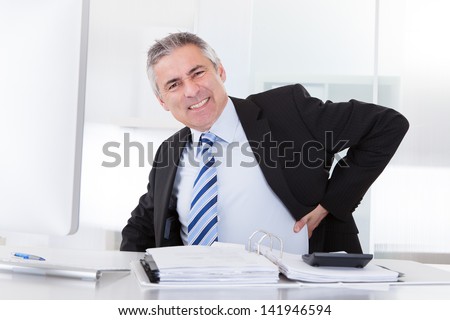 Portrait Of Mature Businessman Suffering From Back Pain