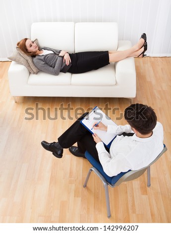 Business woman reclining comfortably on a couch talking to his psychiatrist explaining something