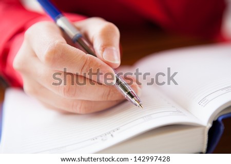 Close-up  of hand holding pen and writing in diary of hand writing in diary