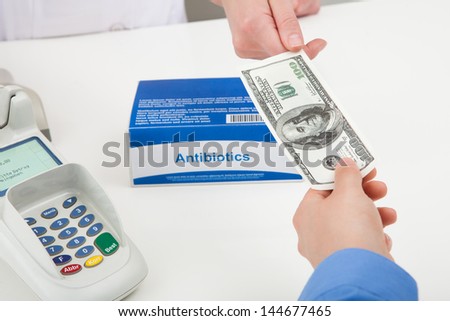 Close-up Of Hand Paying For Medicine Using Cash
