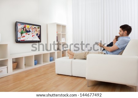 Young couple sitting on couch watching television