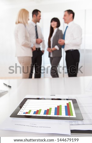 Business People In Conversation And Graph Chart On Table