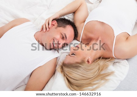 Happy Couple Lying On Bed Looking At Each Other