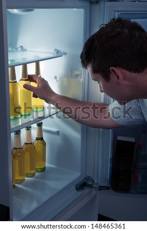 Man choosing bottle of beer from a refrigerator
