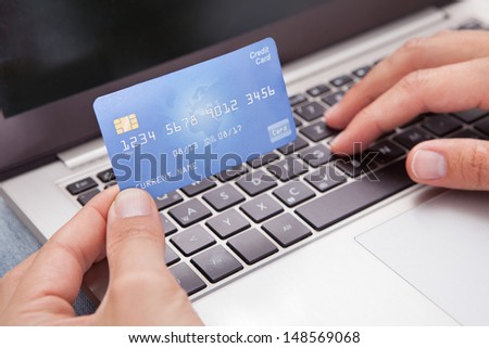 Young Man Sitting With Laptop And Credit Card Shopping Online