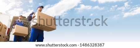 Low Angle View Of Two Young Delivery Man Carrying Cardboard Box In Front Of Truck Stock foto © 