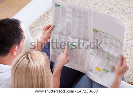 Portrait Of Couple Reading Newspaper Together At Home