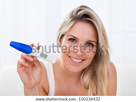 Portrait of a happy young woman holding positive pregnancy test