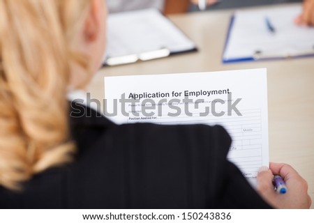 Businesswoman Sitting In Front Of Businessman Holding Application Form