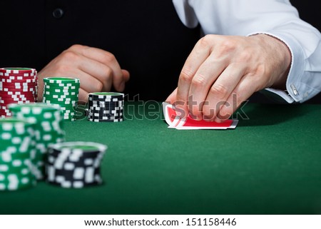 Close-up of a hand of poker player with cards and chips