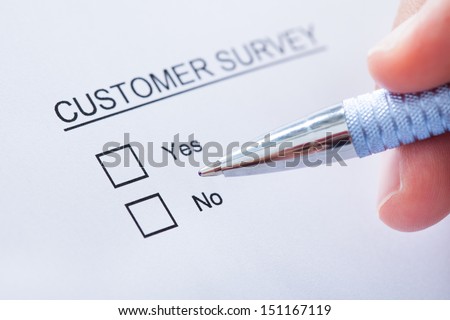 Close-up Of Human Hand Filling Customer Survey Form
