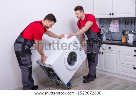 Two Young Male Professional Movers In Uniform Placing The Modern Washing Machine In The Kitchen Photo stock © 