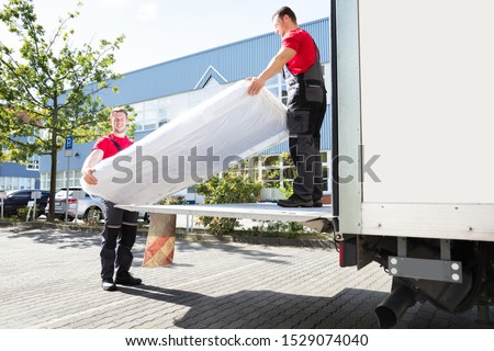 Young Male Movers Unloading The Wrapped Mattress From Moving Truck Photo stock © 