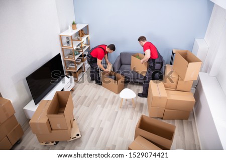 Two Young Movers In Uniform Picking And Putting Products In The Cardboard Boxes Photo stock © 