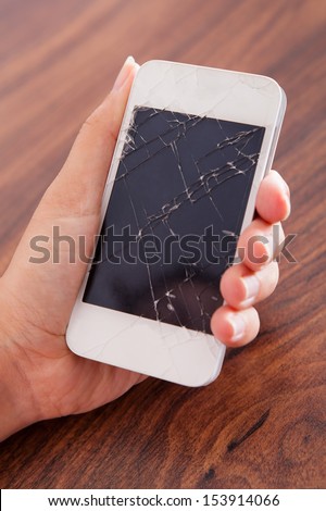 Close-up Of Hand Holding Smartphone With Cracked Screen
