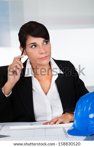 Young Happy Female Architect Working On Blue Print In Office