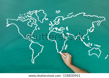 Hand holding chalk drawing world map on blackboard