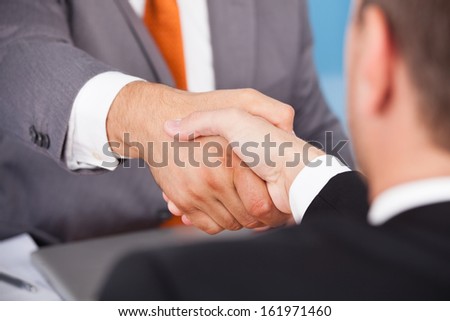 Two Business Partner Shaking Hands In Front Of Colleagues
