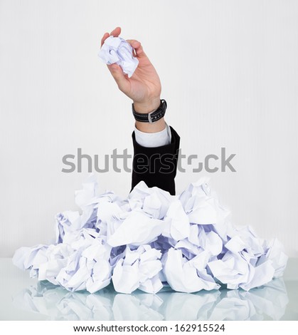 Person Under Pile Of Crumpled Paper With Hand Holding A Paper