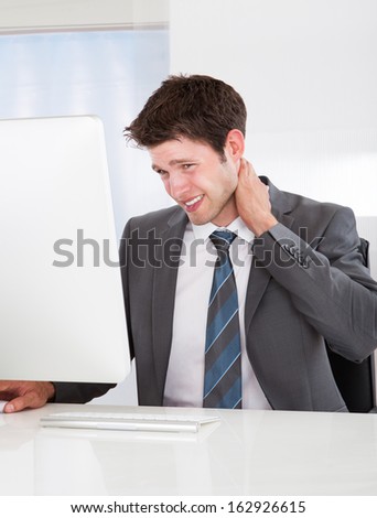 Young Businessman Using Computer Suffering From Neck Ache