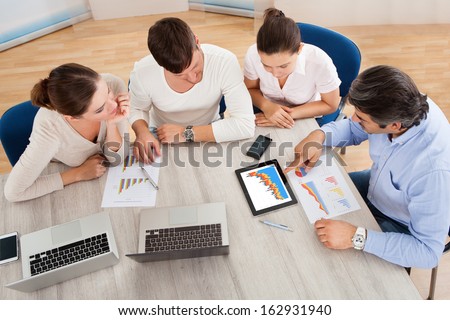 Business Executives At A Meeting Discussing Work On Digital Tablet