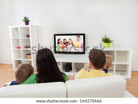 Young happy family watching TV at home