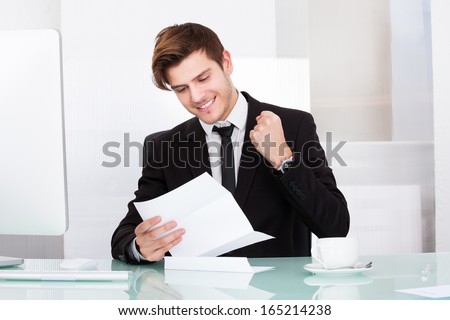 Successful Businessman Clenching His Fist Looking At Paper