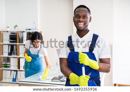 Portrait Of A Happy Male Janitor With Cleaning Equipment In Office Foto stock © 