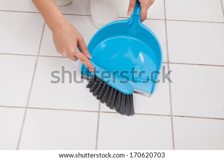 Close-up Of Woman Cleaning Floor With Broom And Dust Pan