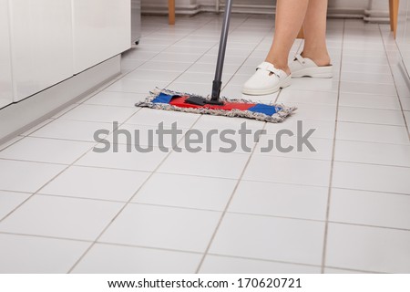 Close-up Of Young Maid In Uniform Cleaning Kitchen Floor