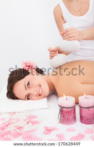 Beautiful Young Woman Getting Herbal Compress Ball Therapy At Spa Salon
