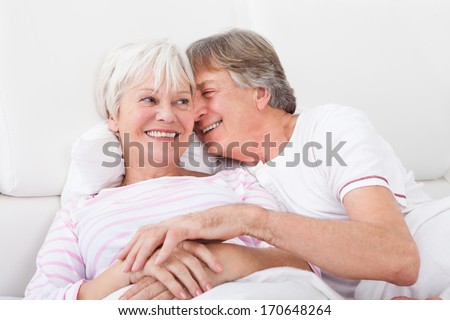 Portrait Of Loving Senior Couple Lying On Bed