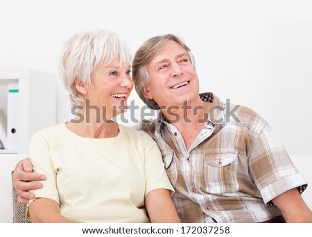 Portrait Of Happy Senior Couple Sitting Together Side By Side Looking Away